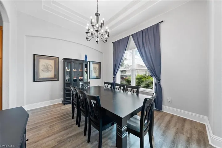 Dining room featuring a raised ceiling, hardwood / wood-style floors, and a chandelier