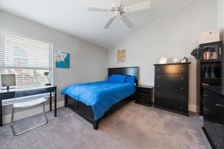 Bedroom with light carpet, ceiling fan, and lofted ceiling