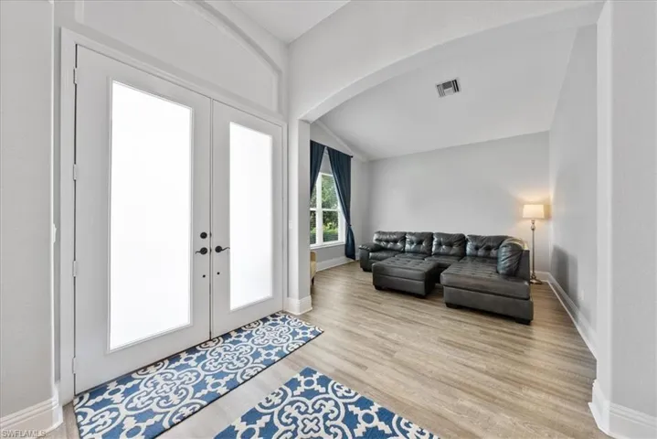 Foyer entrance featuring french doors, lofted ceiling, and light hardwood / wood-style flooring