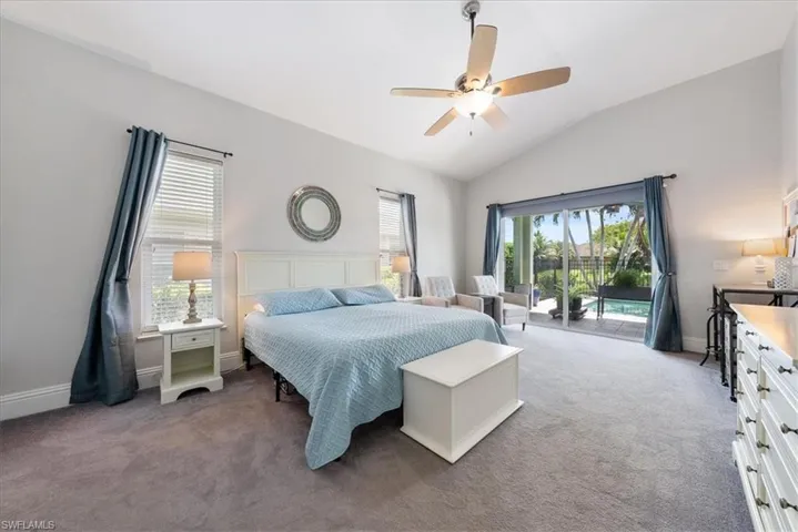 Carpeted bedroom with vaulted ceiling, ceiling fan, access to exterior, and multiple windows