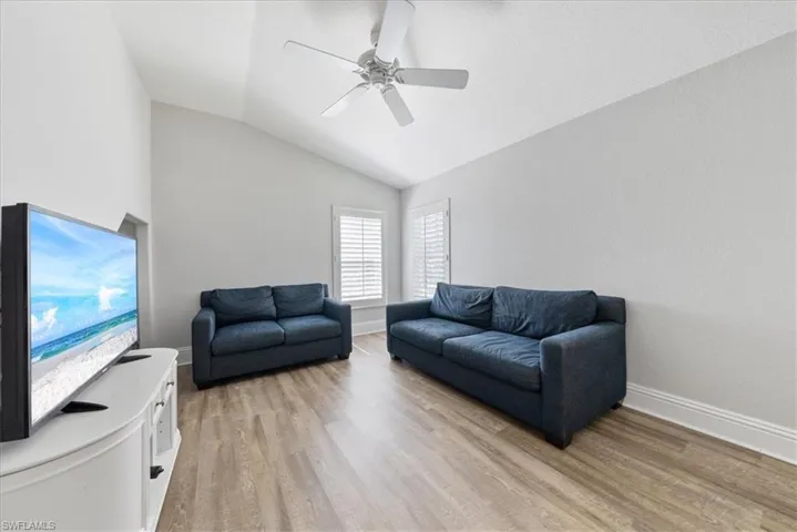 Living room with ceiling fan, vaulted ceiling, and light hardwood / wood-style flooring