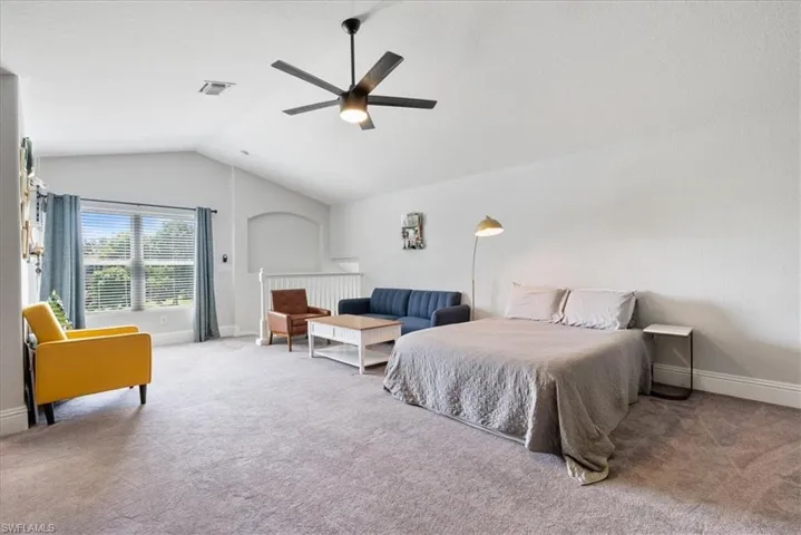 Carpeted bedroom with ceiling fan and lofted ceiling