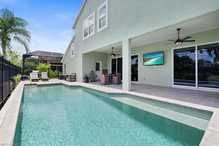 View of swimming pool with ceiling fan, a lanai, and a patio