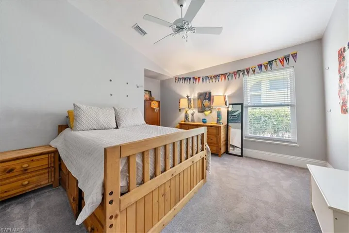 Carpeted bedroom with ceiling fan and vaulted ceiling