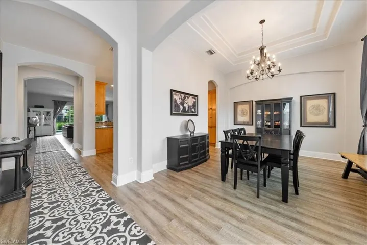 Dining area featuring a tray ceiling, an inviting chandelier, and hardwood / wood-style floors