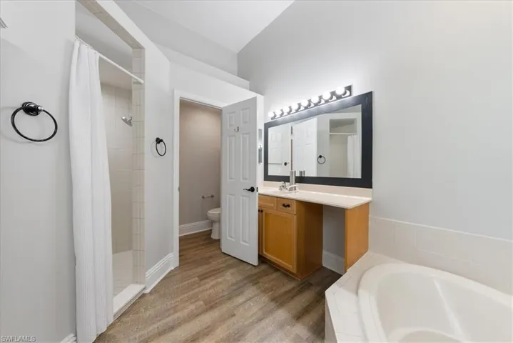 Full bathroom with shower with separate bathtub, hardwood / wood-style flooring, toilet, and vanity
