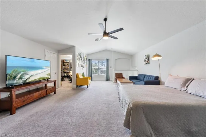 Bedroom featuring a textured ceiling, lofted ceiling, carpet, and ceiling fan