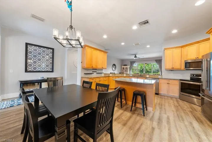Dining area featuring ceiling fan with notable chandelier and light wood-type flooring