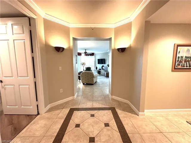 Hallway featuring ornamental molding and light tile floors