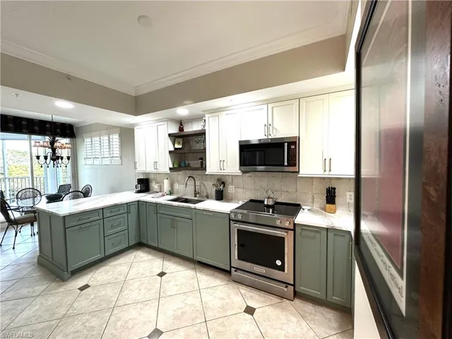 Kitchen with tasteful backsplash, crown molding, white cabinets, sink, and appliances with stainless steel finishes