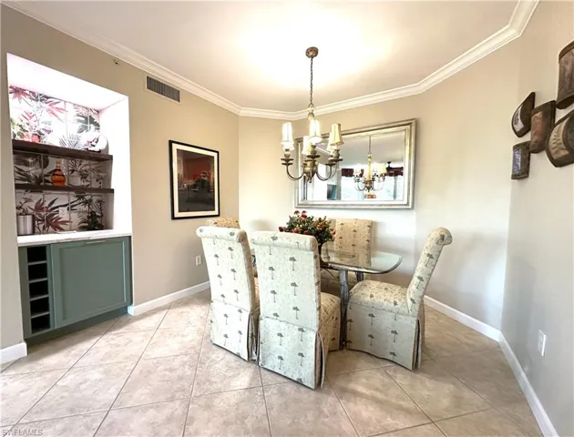 Tiled dining room featuring ornamental molding and a chandelier