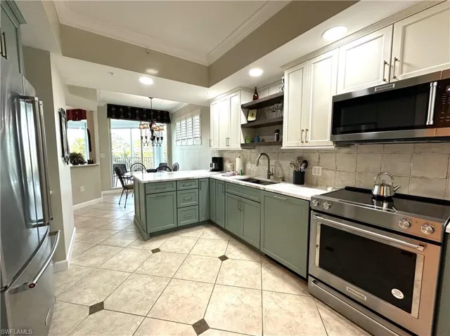 Kitchen featuring tasteful backsplash, white cabinetry, green cabinetry, appliances with stainless steel finishes, and sink
