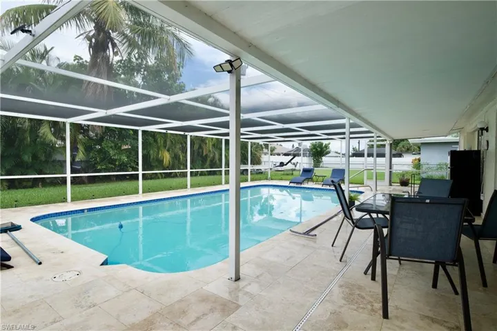 Outdoor pool with a patio area, a lawn, a sunroom, and glass enclosure