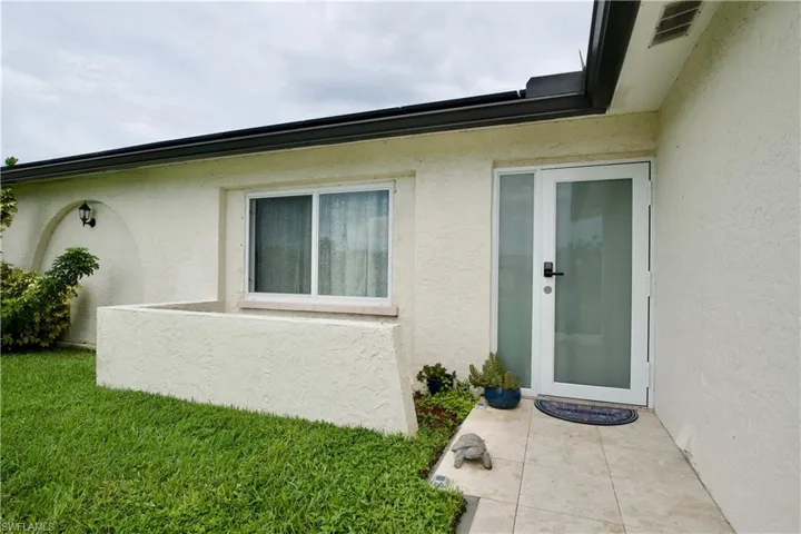 Entrance to property featuring stucco siding and a lawn