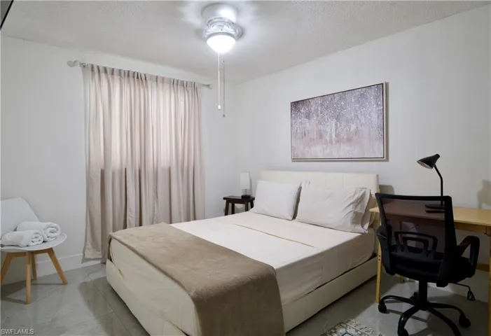 Bedroom featuring a textured ceiling, an office area, and a ceiling fan