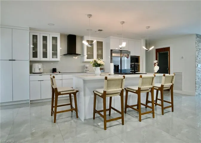 Kitchen with an island with sink, white cabinetry, a breakfast bar, and pendant lighting