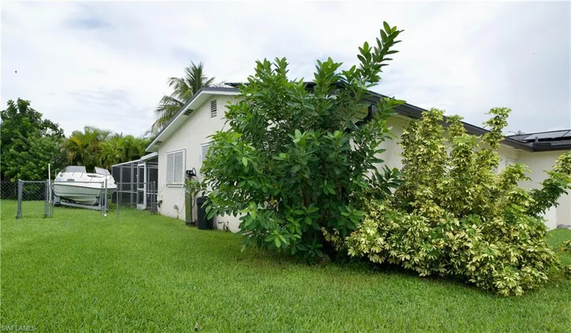 View of side of home featuring stucco siding and a gate