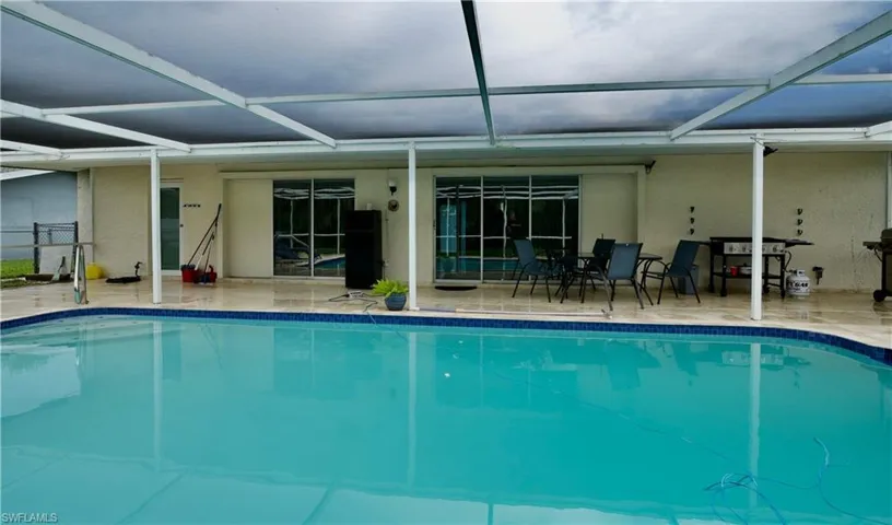 Swimming pool featuring a patio area, a sunroom, and glass enclosure