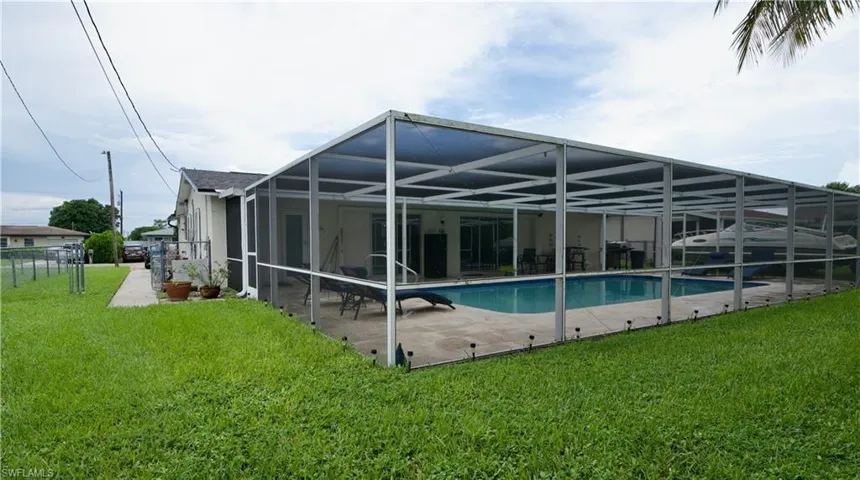 Rear view of property with a patio area, a sunroom, a yard, and a lanai