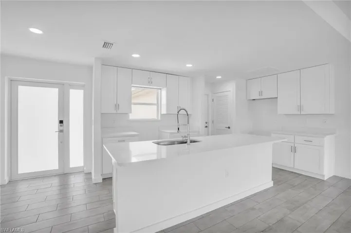 Kitchen with sink, white cabinetry, and an island with sink