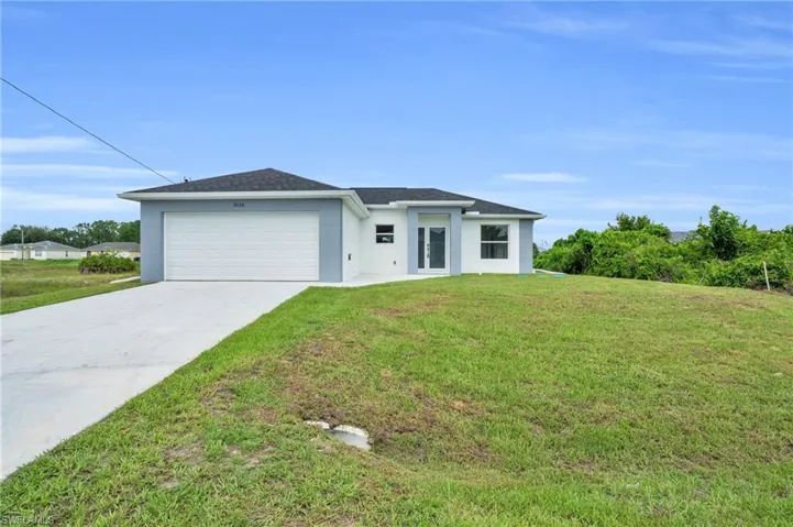 View of front facade featuring a garage and a front lawn