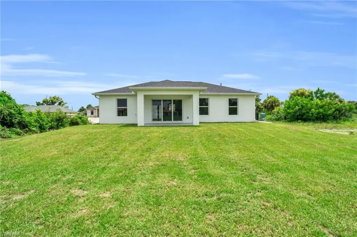 Back of property featuring central air condition unit and a lawn