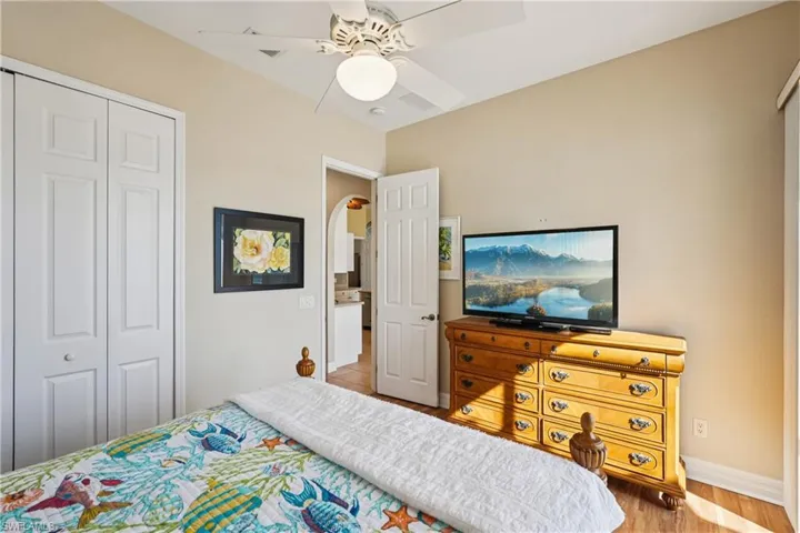 Bedroom with a closet, ceiling fan, arched walkways, and light wood-type flooring