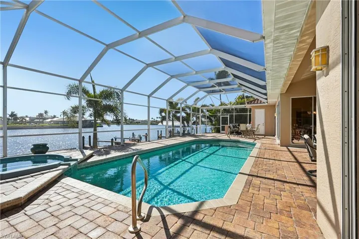 Integrated pool / hot tub featuring a patio, a sunroom, a lanai, a water view, and a boat dock