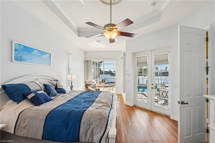 Bedroom featuring access to exterior, ornamental molding, light wood finished floors, a water view, and french doors