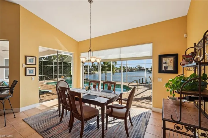 Dining area featuring a sunroom, vaulted ceiling, light tile patterned floors, and a water view