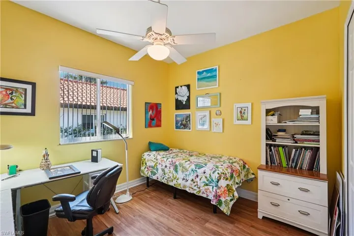 Bedroom featuring light wood-style floors, ceiling fan, and an office area