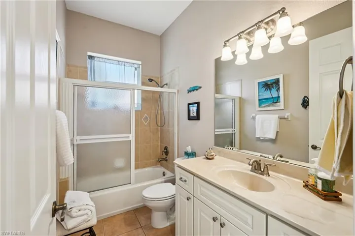 Bathroom with vanity, shower / bath combination with glass door, and light tile patterned flooring