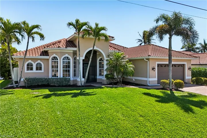 Mediterranean / spanish-style house featuring stucco siding, an attached garage, a front lawn, and a tile roof