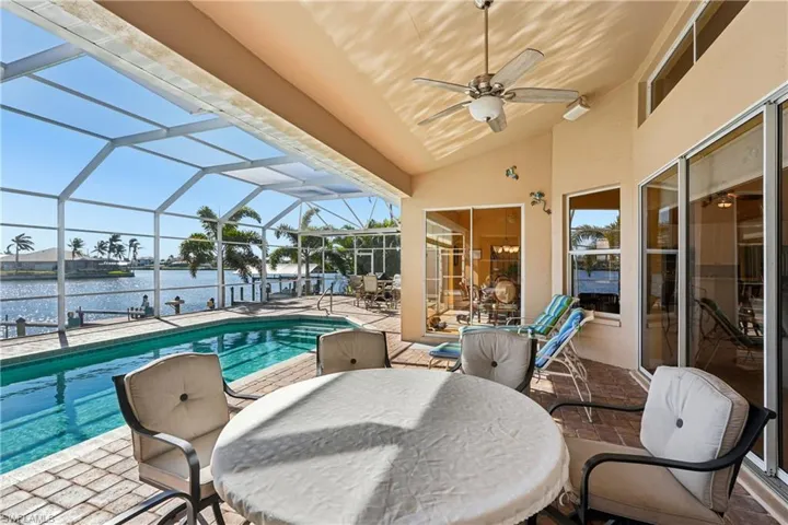 Outdoor pool featuring outdoor dining space, a patio area, a lanai, a sunroom, and a water view