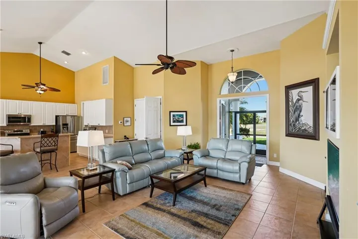 Living area with a ceiling fan, light tile patterned flooring, and lofted ceiling