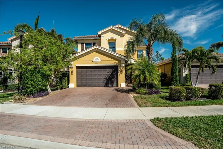 Grand Mediterranean-style entrance with an extended paver driveway, lush landscaping, and elegant architectural details, showcasing the pinnacle of Naples luxury living in Riverstone Naples Florida