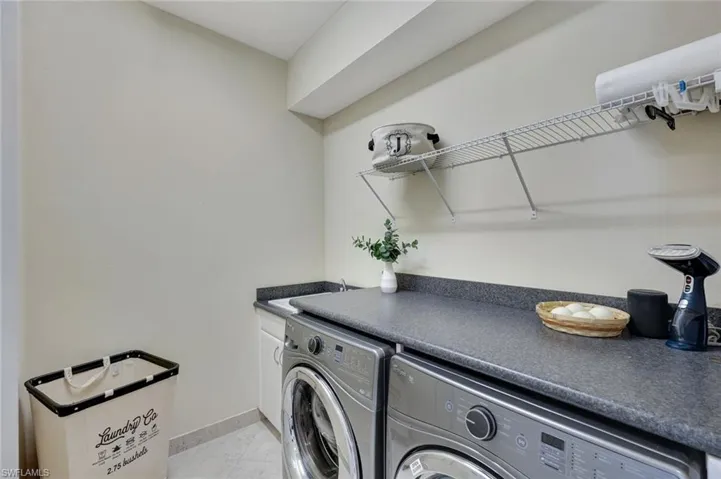 This laundry room blends functionality and innovation, featuring front-loading Whirlpool washer and dryer appliances for efficient and stylish care. Ample cabinetry and a utility sink provide convenience and storage, while the smart home hub centralizes all internet, alarm, cable, and connectivity systems to seamlessly supply the entire home. With its modern design and high-tech amenities, this space is built to simplify your day-to-day task