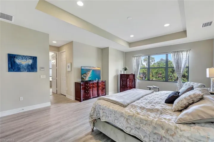 * An expansive and luxurious master suite designed for ultimate comfort and elegance. Featuring raised ceilings, premium light wood vinyl flooring, and oversized windows, the space is flooded with natural light and showcases serene views. With ample room for a sitting area or additional furnishings, this suite is the perfect private retreate Automated for turning overhead led lights and table laps on it off just be speaking to what you would like it to do