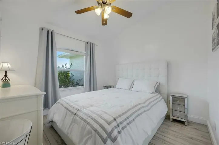 Bedroom featuring a ceiling fan, wood finished floors, and vaulted ceiling
