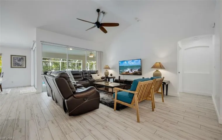 Living room with ceiling fan, light wood-style floors, lofted ceiling, and a sunroom