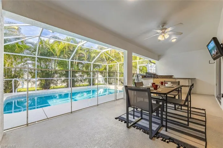 Swimming pool featuring a patio, a sunroom, glass enclosure, and an outdoor kitchen / dining area