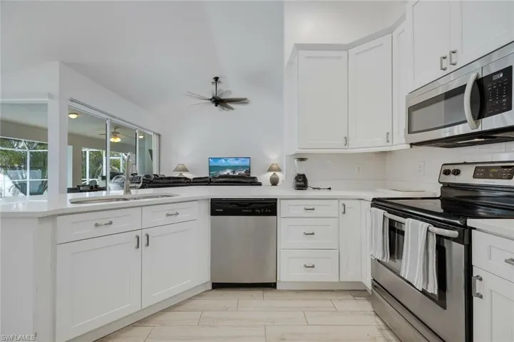 Kitchen featuring stainless steel appliances, white cabinetry, and a peninsula