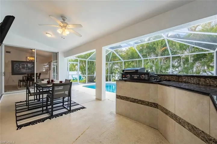 Outdoor pool with outdoor dining space, a patio area, a sunroom, and glass enclosure