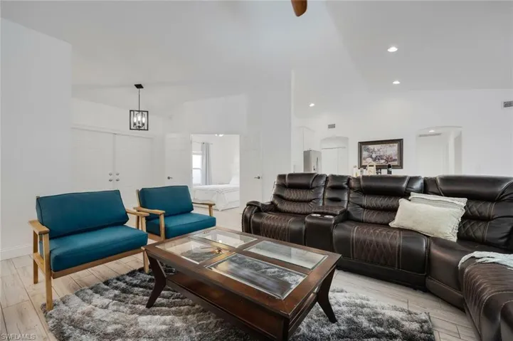 Living room with light wood-type flooring, lofted ceiling, a ceiling fan, and recessed lighting