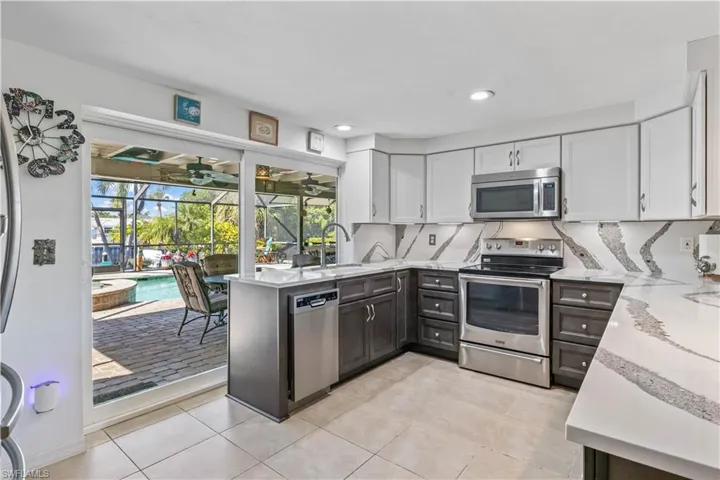 Open-concept kitchen with breakfast bar, connecting indoor dining to the lanai and pool area.