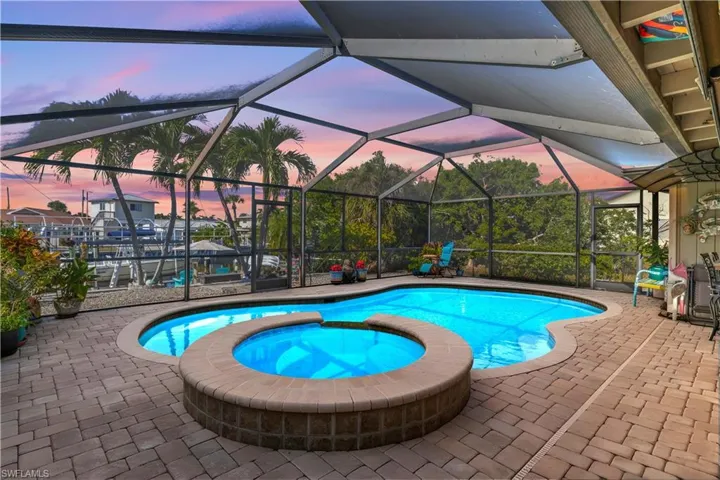 Sparkling saltwater pool and spa with a stunning Florida sunset reflecting on the water.