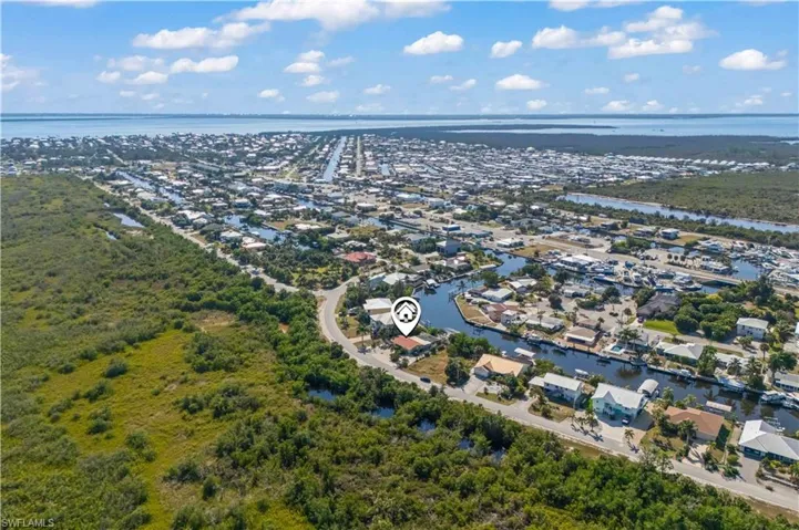 Drone perspective capturing the full property layout, private dock, and vivid sunset over the Gulf of Mexico.