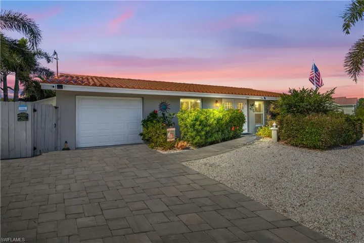 Stunning single-family waterfront home with a custom paver driveway, tropical landscaping, and low-maintenance zero scaping for effortless beauty.