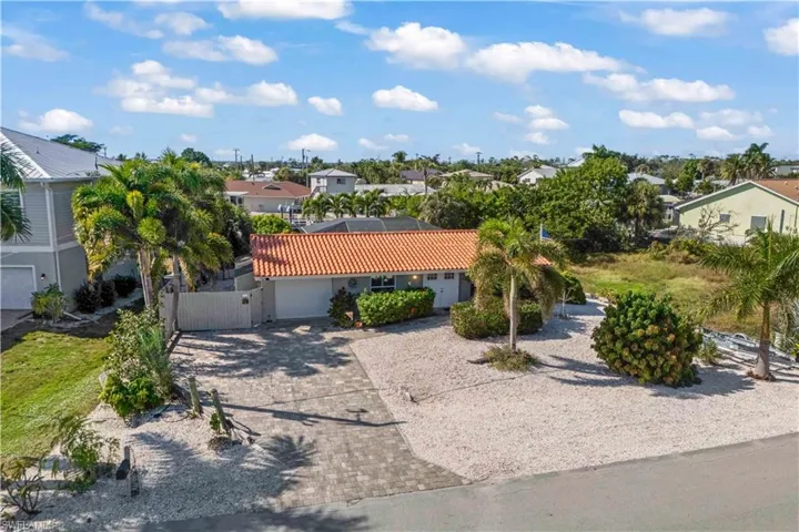 View of the driveway, entryway, and lush landscaping that frames this stunning waterfront home.