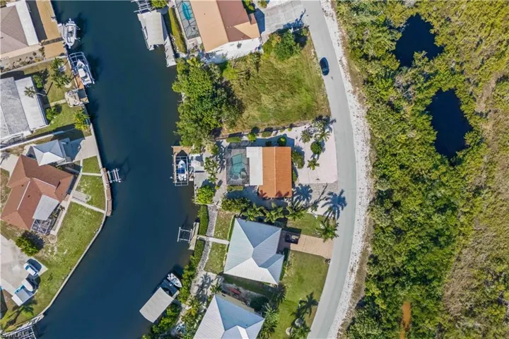 High-angle drone view from above, highlighting the pool, spa, dock, and overall property layout.